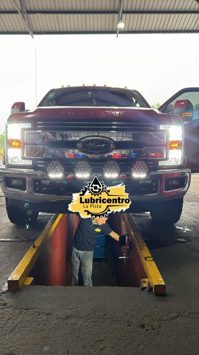 Pickup sobre la fosa del taller, con el emblema de Lubricentro La Pista al frente